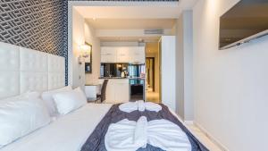 a bedroom with a white bed and a kitchen at Art Luxury Suites in Pefkohori