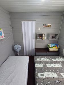 Cette petite chambre comprend un lit et une porte. dans l'établissement Casa de Praia Juli e Vini, à Cidreira
