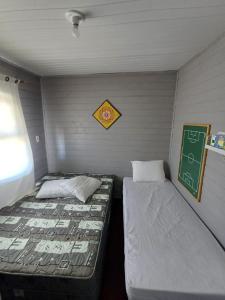 2 camas en una habitación pequeña con pizarra en Casa de Praia Juli e Vini, en Cidreira