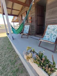 een veranda met een hangmat, een stoel en een cactus bij Casa de Praia Juli e Vini in Cidreira
