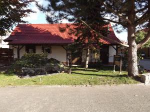 uma casa com um telhado vermelho e uma árvore em Pension Regenbogen em Stralsund