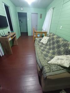 een slaapkamer met een bed, een bureau en een televisie bij Casa de Praia Juli e Vini in Cidreira