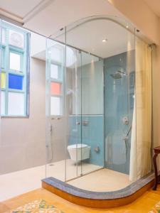 a bathroom with a glass shower with a toilet at Villa Kouga in Puducherry