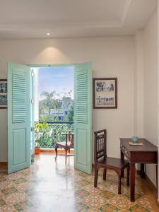 Habitación con puerta, mesa y escritorio. en Villa Kouga en Pondicherry