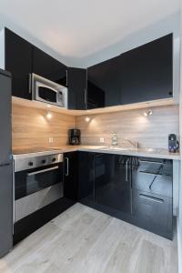 een keuken met zwarte kasten en een magnetron bij Lille, fully-equipped apartment with parking space in Lille