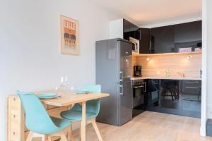een keuken met een houten tafel en blauwe stoelen bij Lille, fully-equipped apartment with parking space in Lille