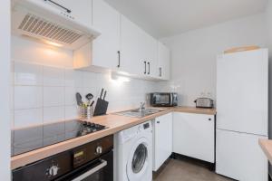 uma cozinha com armários brancos e uma máquina de lavar e secar roupa em Spacious apartment with parking and balcony! em Lille