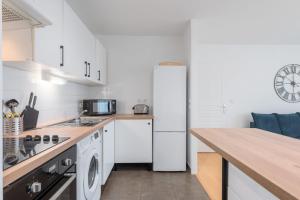 een keuken met witte kasten en een witte koelkast bij Spacious apartment with parking and balcony! in Lille