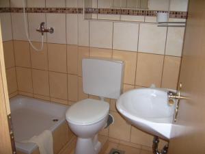 a bathroom with a toilet and a sink and a tub at Pension Regenbogen in Stralsund