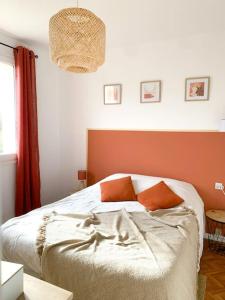 een bed met 2 oranje kussens in een slaapkamer bij la maison du vignoble in La Limouzinière