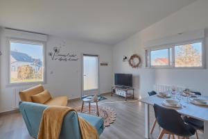 sala de estar con mesa, sillas y TV en La Petite Maison Cocooning - De plain pied, en Mésanger