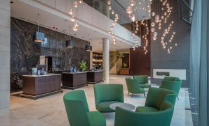 a lobby with green chairs and a salon at Radisson Blu Royal Hotel Dublin in Dublin