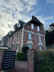 ein großes rotes Backsteingebäude mit einem Dach in der Unterkunft Le Magnolia Maison 12 Couchages in Dieppe
