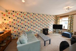 a living room with a couch and a television at Pottery Cottage, Lochans Lodge in Stranraer