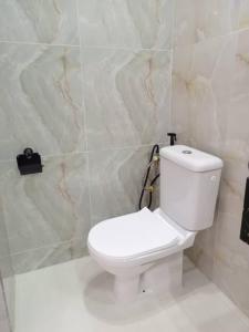 a bathroom with a white toilet in a room at Entré Quartier Jack in Cotonou
