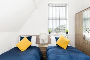 バーミンガムにあるSapphire Suite Moseley Mews by StayStaycationsの- 青と黄色の枕付きのベッド2台