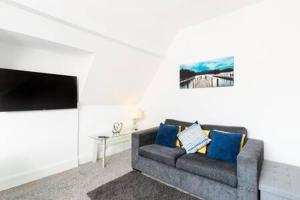 a living room with a gray couch with blue pillows at Sapphire Suite Moseley Mews by StayStaycations in Birmingham