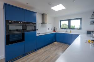 cocina azul con paredes blancas y suelo de madera en Home Reach 4 en Aldeburgh