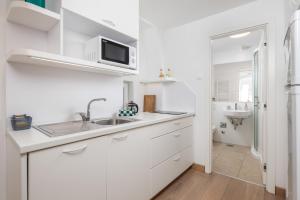 a white kitchen with a sink and a microwave at Apartments Anaika at the beach, Opatija in Ika +48 photos