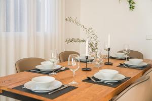 a wooden table with plates and wine glasses on it at Traumhafte Villa Marisol für 8 Gäste am Meer in Alcudia +21 photos