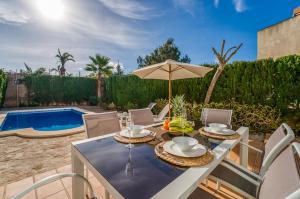 tavolo e sedie con ombrellone e piscina di Traumhafte Villa Marisol für 8 Gäste am Meer a Alcudia