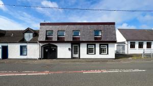 una casa blanca con techo marrón en una calle en Pottery Cottage, Lochans Lodge en Stranraer