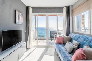 uma sala de estar com um sofá azul e uma televisão em Primera línea de playa em Alicante