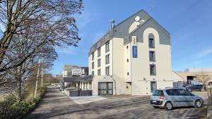 een auto geparkeerd voor een wit gebouw bij The Originals City, Hôtel Orléans Nord (Inter-Hotel) in Saran