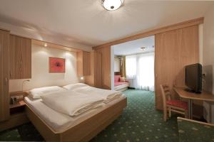 um quarto com uma cama, uma secretária e uma televisão em Hotel Gratz Großarl em Grossarl