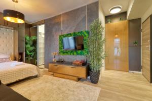 um quarto com uma cama e uma televisão na parede em Herastrau Luxury Studios em Bucareste