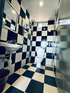 a checkered bathroom with a toilet and a sink at CassaKaseh Guest House in Pantai Cenang