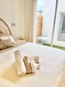 two rolled towels on a white bed with a window at CHAMBRE d'Hôtes avec PISCINE & KITCHENETTE in Saint-Geniès-des-Mourgues