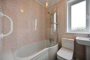 a bathroom with a tub and a toilet and a sink at Lochans Lodge in Stranraer
