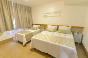 a hotel room with two beds and a window at Topázio Pousada in Morro de São Paulo