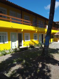 un edificio giallo con una palma di fronte di Suíte Sunflower 103 a Rio das Ostras