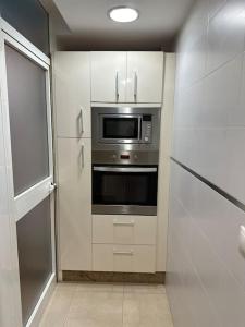 a kitchen with white cabinets and a stainless steel oven at Apartamento turístico O.N Renfe in Córdoba