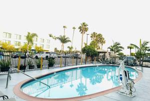 duży basen z ogrodzeniem i palmami w obiekcie Ramada by Wyndham San Diego Airport w mieście San Diego