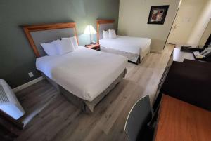 a hotel room with two beds and a desk at Ramada by Wyndham Houston Intercontinental Airport East in Humble