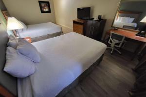 a hotel room with a bed and a desk with a mirror at Ramada by Wyndham Houston Intercontinental Airport East in Humble