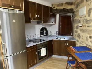 uma cozinha com armários de madeira e um frigorífico de aço inoxidável em Casa Bralo em Padrón