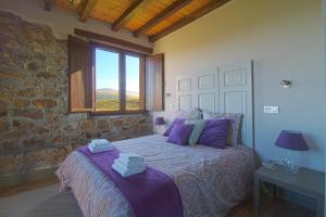 - une chambre avec un lit doté de draps violets et une fenêtre dans l'établissement Casona Alto Sarracin, à Penagos