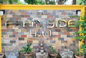 una señal para un hotel en una pared de ladrillo con plantas en RedDoorz @ Farm Side Hotel Laoag City en Laoag