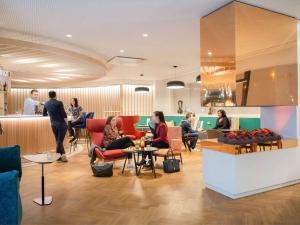 a lobby with people sitting in chairs and a bar at Novotel Le Havre Centre Gare in Le Havre