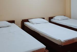 2 bedden in een kamer met witte lakens en kussens bij RedDoorz @ Farm Side Hotel Laoag City in Laoag