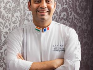 un homme en uniforme de chef debout avec les bras croisés dans l'établissement Sofitel Mumbai BKC, à Mumbai