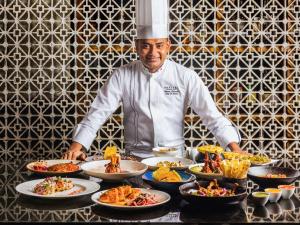 a chef standing in front of a table of food at Sofitel Mumbai BKC in Mumbai
