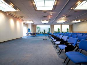 an empty room with blue chairs and tables at Novotel Caserta Sud in Caserta