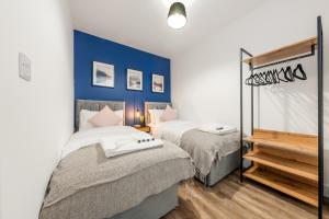 a bedroom with two beds and a blue wall at The Hertfordshire Hideaway in Potters Bar