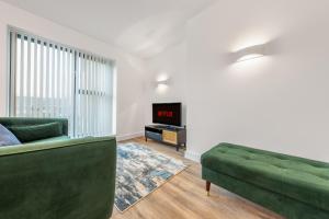 a living room with a green couch and a tv at The Hertfordshire Hideaway in Potters Bar