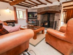 a living room with leather furniture and a stone fireplace at Rockhill Farmhouse in Craven Arms